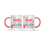 Zwei weiße Tassen mit rotem Henkel, beide mit dem Spruch „Ein Stift, die alle bluten lassen“ – humorvolle Geschenkidee für Lehrer.